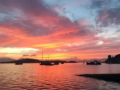 a sunset over a body of water with boats at Finlaggan Apartment in Oban