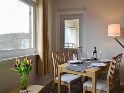a dining room with a table and chairs and a window at Finlaggan Apartment in Oban
