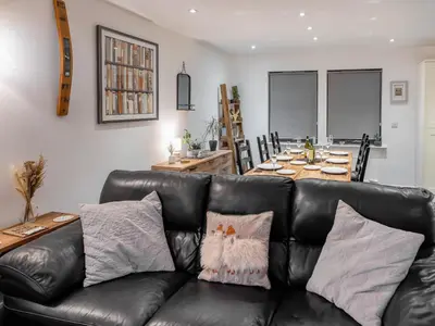 a living room with a black leather couch and a table at Thistlebank in Banknock