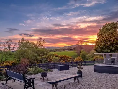 a patio with a bench and a sunset in the background at Thistlebank in Banknock