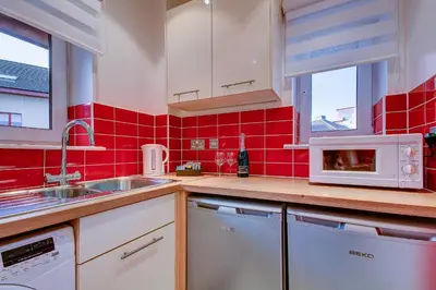 a red tiled kitchen with a sink and a microwave at No 7 Ayr Beach - Coorie Doon in Ayr