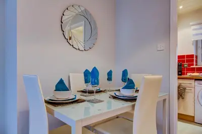 a dining room with a table and chairs and a mirror at No 7 Ayr Beach - Coorie Doon in Ayr