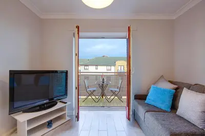 a living room with a couch and a tv and a balcony at No 7 Ayr Beach - Coorie Doon in Ayr