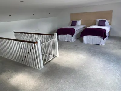 two beds sitting in a room with carpet at The Village Tavern Apartment in Larkhall