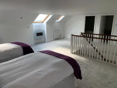a bedroom with two beds and a staircase with skylights at The Village Tavern Apartment in Larkhall