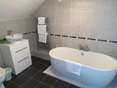 a bathroom with a white tub and a sink at The Village Tavern Apartment in Larkhall