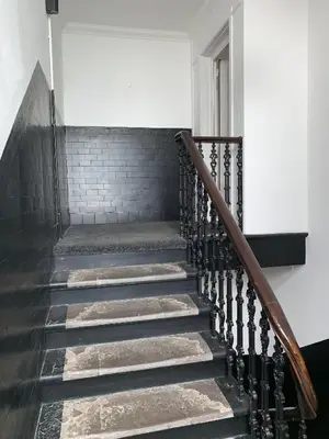 a staircase in a house with black and white tiles at The Village Tavern Apartment in Larkhall