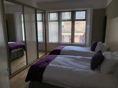 a bedroom with two beds and a large window at The Village Tavern Apartment in Larkhall