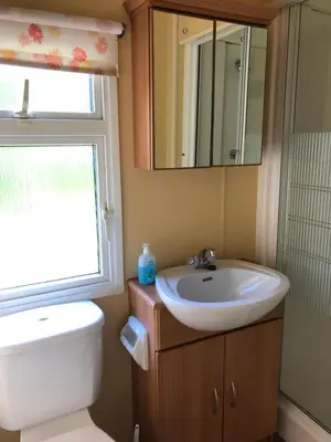 a bathroom with a sink and a toilet and a mirror at 40 Glenfinart Caravan Park in Dunoon