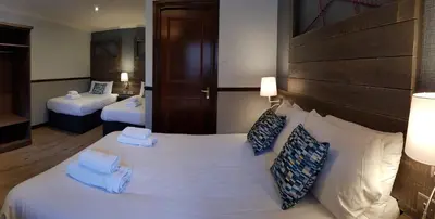 a hotel room with a large white bed with blue pillows at Clachaig Inn in Ballachulish