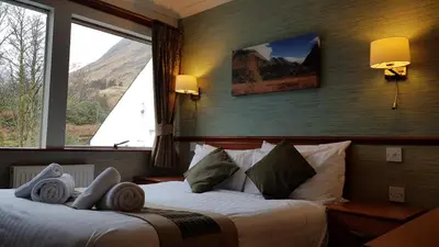 a hotel room with two beds and a large window at Clachaig Inn in Ballachulish