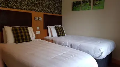two beds in a hotel room with white sheets at Clachaig Inn in Ballachulish