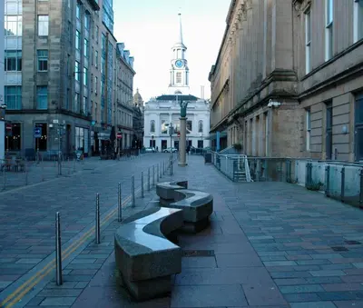 a city street with benches and a building with a clock tower at The Socair - Bright Contemporary Merchant City Flat in Central Location in Glasgow