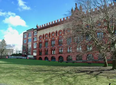 a large brick building with a tree in front of it at The Socair - Bright Contemporary Merchant City Flat in Central Location in Glasgow