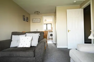 a living room with a couch and a chair at ArcView - SEC Hydro Two Bed Flat With Free parking and Great View in Glasgow