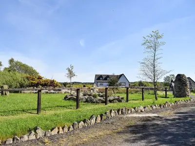 a pasture with a fence and a house in the background at Lawford Lodge in Bonnybridge