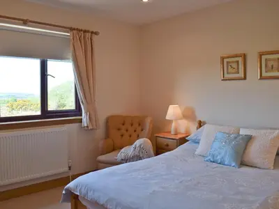 a bedroom with a bed and a chair and a window at Lawford Lodge in Bonnybridge