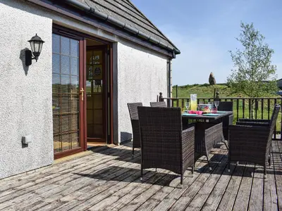 a patio with a table and chairs on a deck at Lawford Lodge in Bonnybridge