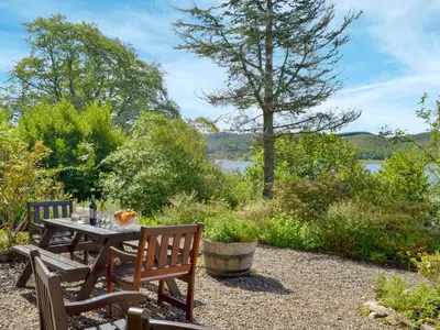 a table and chairs with a view of a lake at Dunyvaig in Colintraive
