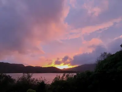 a sunset over a body of water with mountains at Dunyvaig in Colintraive