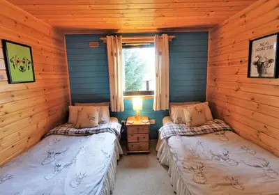 a bedroom with two beds in a log cabin at Glen Bay - 2 Bed Lodge on Friendly Farm Stay with Private Hot Tub in New Cumnock