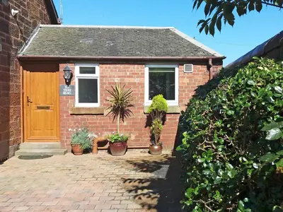 a brick house with potted plants in front of it at Tigh Beag in Troon