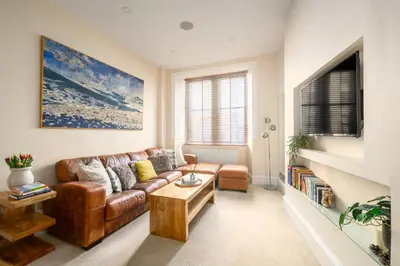 a living room with a brown leather couch and a table at Stylish & Central 2BR Stockbridge Gem in Edinburgh