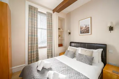 a bedroom with a bed with white sheets and a window at Stylish & Central 2BR Stockbridge Gem in Edinburgh