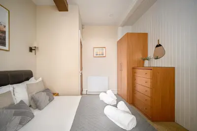 a bedroom with a white bed and a wooden dresser at Stylish & Central 2BR Stockbridge Gem in Edinburgh