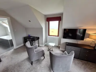 a living room with two chairs and a desk and a television at Lochview Guesthouse in Corran