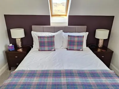 a bedroom with a bed with two pillows and two lamps at Lochview Guesthouse in Corran