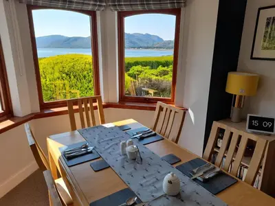 a dining room with a table and two windows at Lochview Guesthouse in Corran