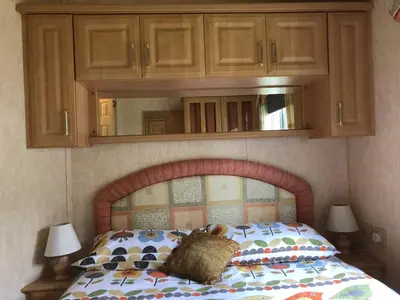 a bedroom with a bed with a headboard and cabinets at Bermuda 29 in Dunoon