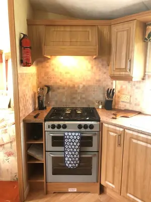 a kitchen with a stove and wooden cabinets at Bermuda 29 in Dunoon