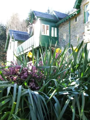 a garden with purple flowers in front of a house at Auchmore Apartments in Killin