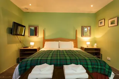 a bedroom with a large bed with green walls at Powdermills B & B in Inveraray