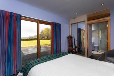 a bedroom with a bed and a large window at Powdermills B & B in Inveraray