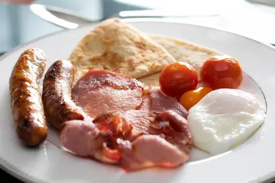 a plate of breakfast food with eggs sausage and tomatoes at Powdermills B & B in Inveraray