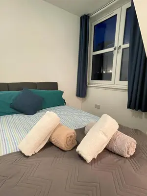 a bedroom with two towels on a bed with a window at Carvetii - Edward House D - 2 Dbl bed 2nd floor flat in Dunfermline