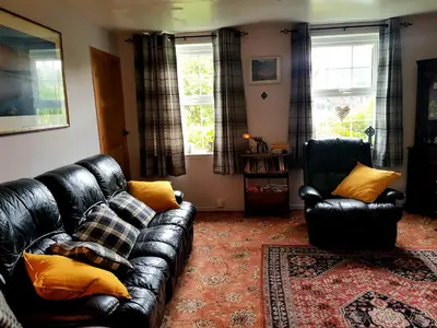 a living room with a leather couch and two chairs at Argyllholidaycottage Loch Awe in Eredine