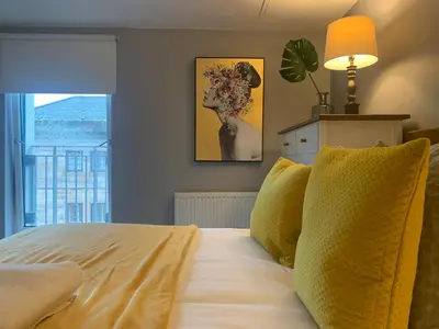 a bedroom with a bed with yellow pillows and a window at Merchant City Modern 1 Bed Executive Flat in Glasgow