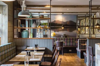 a restaurant with tables and chairs and a wall mural at The Kilchrenan Inn in Oban