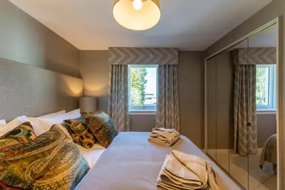 a bedroom with a large bed and a mirror at Gleneagles Apartment - Guthrie Court Gleneagles in Auchterarder