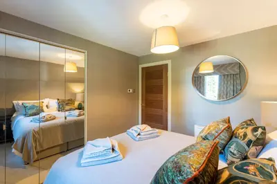 a bedroom with two beds and a mirror at Gleneagles Apartment - Guthrie Court Gleneagles in Auchterarder