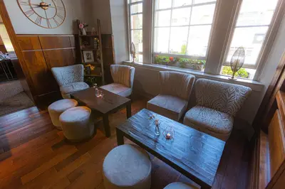 a living room with a table and chairs and a clock at Fletcher's Restaurant Bar & Rooms in Stirling