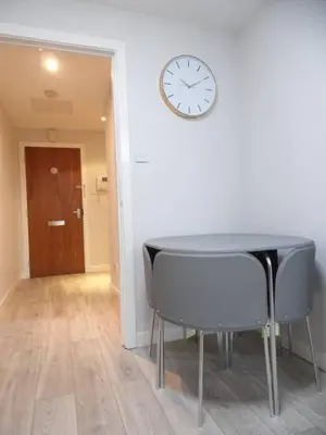 a table and chairs in a room with a clock on the wall at Art Deco Building on Vibrant Sauchiehall Street in Glasgow