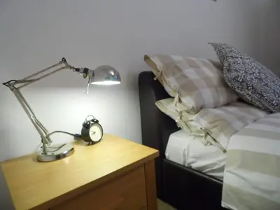 a lamp on a wooden table next to a bed at Modern 2-bedroom Apt near SSE Hydro and SEC in Glasgow