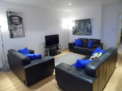 a living room with black leather couches and blue pillows at Modern 2-bedroom Apt near SSE Hydro and SEC in Glasgow