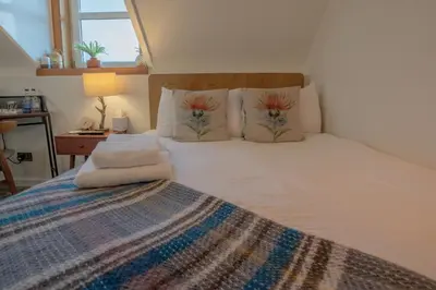 a bedroom with a large white bed with flowers on the pillows at Cardross Inn in Cardross