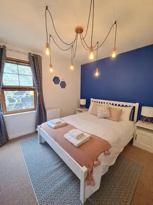 a bedroom with a large bed with a blue wall at Six Stevenson House, Oban in Oban